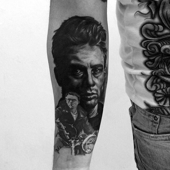 Black and grey forearm tattoo of James Dean’s serious expression above a scene of him riding a motorcycle.