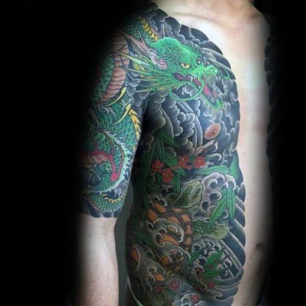 Japanese-style tattoo featuring a green dragon and a turtle, surrounded by waves and floral elements, creating a bold and intricate design.