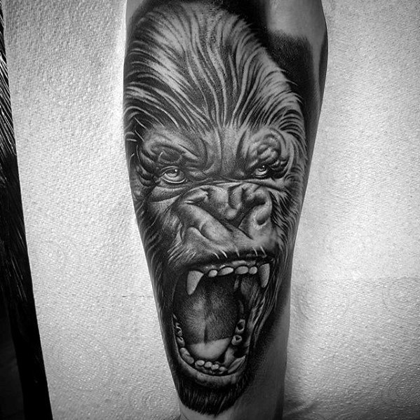Black and grey King Kong tattoo on leg featuring a fierce close-up of Kong roaring with sharp detail and intense expression.