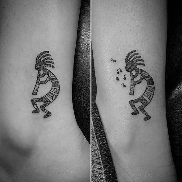 Matching Kokopelli tattoos in black ink with tribal patterns, one with musical notes and symbols floating from the flute.