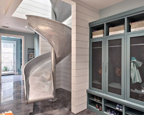 A modern living space features a spiral slide beside built-in storage and an open doorway