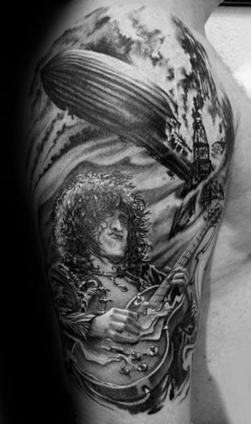 Black and gray upper arm tattoo of Jimmy Page with a Zeppelin airship explosion in the background, symbolizing Led Zeppelin.