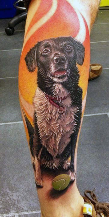 Tattoo of a black and white dog with a tennis ball and an orange background on a leg