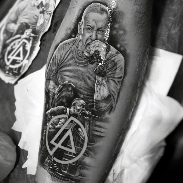 Hyper-realistic black and gray tattoo of Chester Bennington performing, featuring detailed shading and the Linkin Park logo.