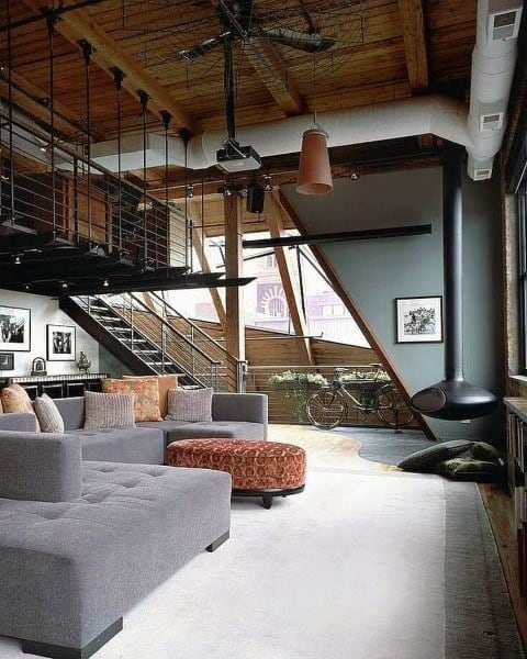 Industrial loft living room with wood ceiling, modern fireplace, and cozy gray sectional sofa.