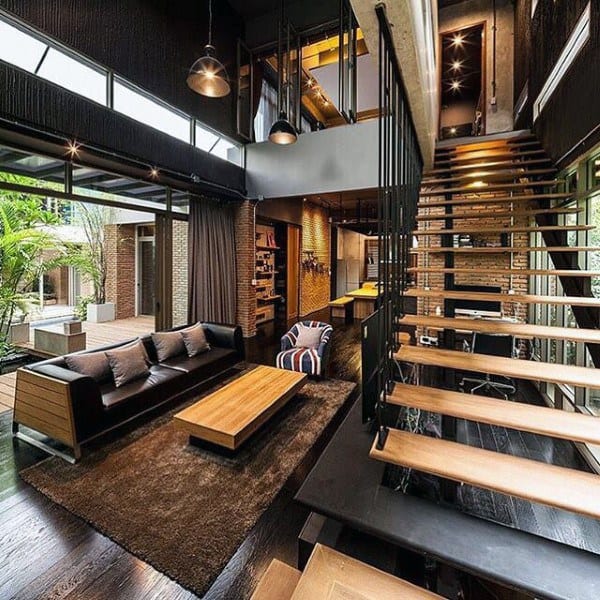 Industrial loft with open living area, wooden floating staircase, and exposed brick accents.