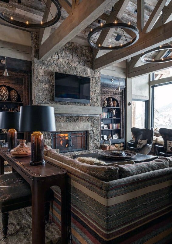 Cozy log cabin interior with stone fireplace, vaulted ceiling, rustic furniture, and warm lighting.