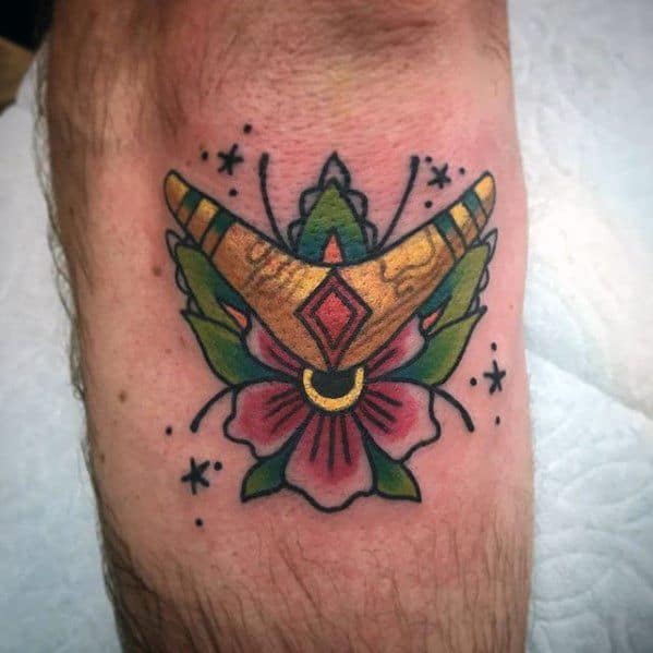 Colorful boomerang tattoo over a flower with butterfly wings and star accents, blending traditional and mystical elements.