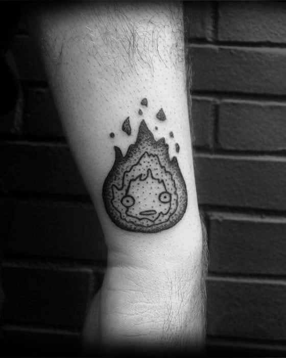 Blackwork Calcifer tattoo with textured flame details, a concerned expression, and bold dotwork shading on the forearm.