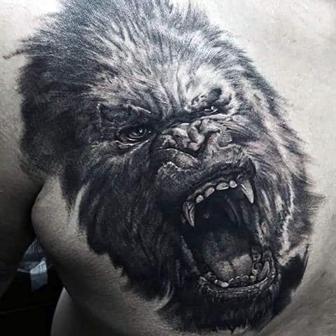 Realistic roaring King Kong tattoo on chest with dynamic shading, showcasing intense eyes and fierce open mouth with sharp teeth.