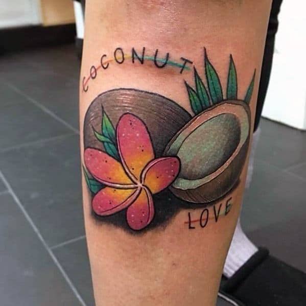 Colorful tattoo of two coconuts, tropical leaves, a pink plumeria flower, and the words "Coconut Love" on the lower leg.