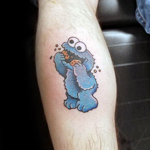 Cute Cookie Monster tattoo in cartoon style, joyfully eating cookies with crumbs flying around on a light skin background.