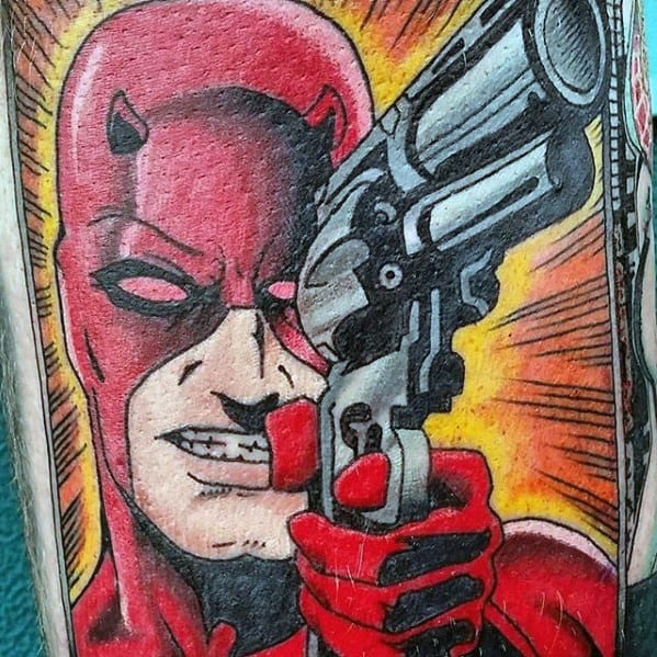 Comic-style Daredevil tattoo featuring a bold red suit and intense expression while aiming a large revolver with a fiery background.