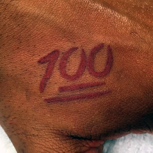 Tattoo of "100" with two lines underneath on a person's hand, resembling the emoji