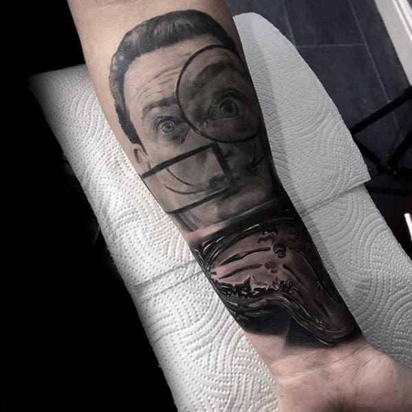 Black and grey Salvador Dali tattoo on forearm with surreal split-face design and melting clock detail inspired by The Persistence of Memory.