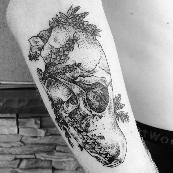 Dotwork tattoo of a fox skull with floral elements and leaves, blending nature and decay on the upper arm.