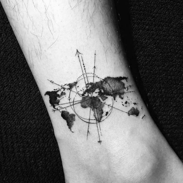 World map and compass tattoo on ankle with fine lines and watercolor-style shading, symbolizing travel and exploration.