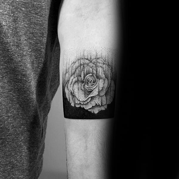 Black and grey gradient tattoo of a blooming rose, fading into dotwork at the top and framed by a solid black band at the bottom.