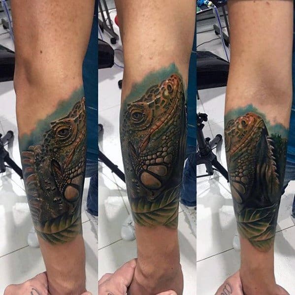 Realistic iguana forearm tattoo with earthy tones, green foliage, and detailed scale work wrapping around the arm.