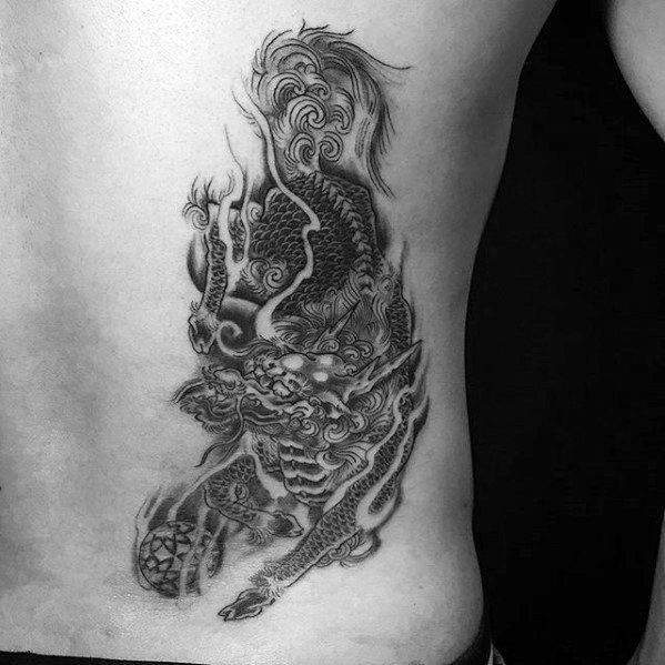 Black and grey Kirin tattoo on the ribs, featuring flowing fur, intricate scales, and a fierce gaze in a dynamic, smoky composition.