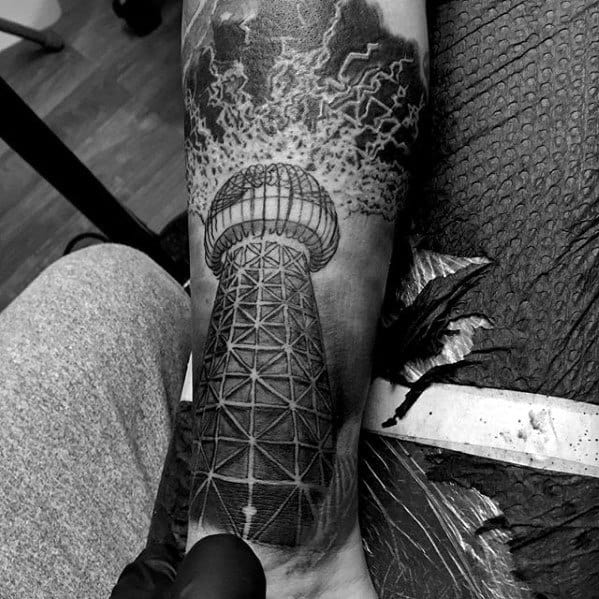 Black and grey tattoo of Tesla’s Wardenclyffe Tower with lightning bolts and storm clouds bursting from the top.