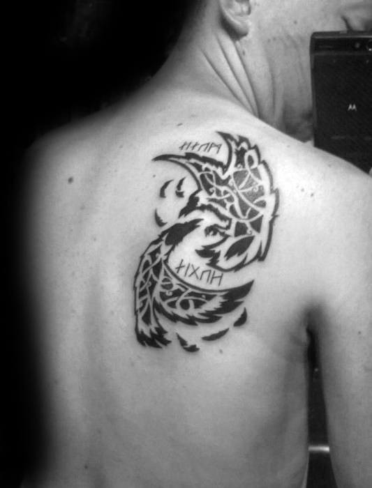 Tribal-style Odin’s ravens tattoo with Huginn and Muninn circling a Norse symbol, inked on the upper back.