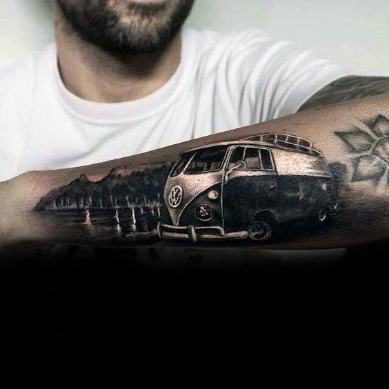 Volkswagen camper van tattoo on forearm with a lakeside mountain scene in detailed black and gray realism.
