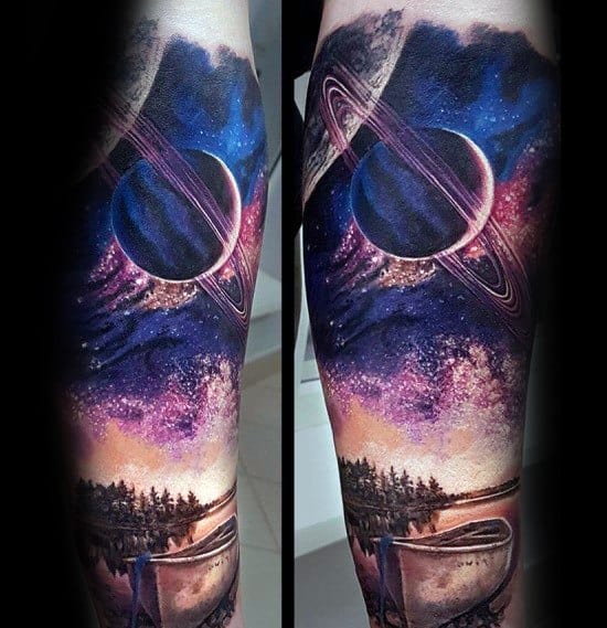 Alt text: Cosmic tattoo with a stunning galaxy scene featuring Saturn, a canoe on a lake, and a starry sky blending into a surreal space theme.