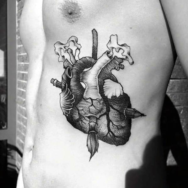 A pencil-drawn black and white tattoo of an anatomical heart graces a person's side