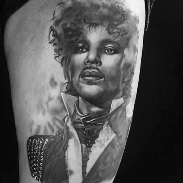 Realistic black-and-gray tattoo of Prince, showcasing his signature style and charismatic expression.