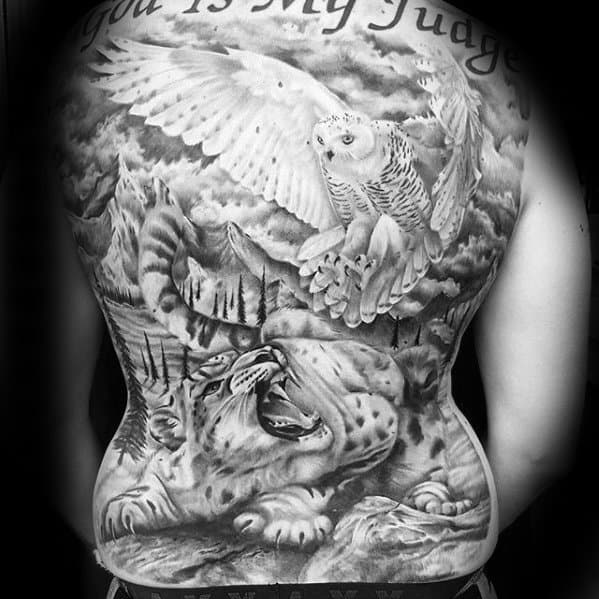 Full-back snow leopard tattoo in black and gray, featuring a roaring leopard below a soaring owl amid dramatic mountains and clouds.
