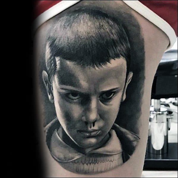 Black and grey tattoo of Eleven from Stranger Things with a serious stare and nosebleed, capturing her intense psychic moment.