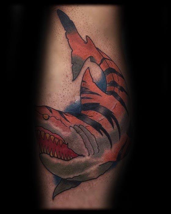 A vibrant tigar shark tattoo with blue, red, and black colors on skin