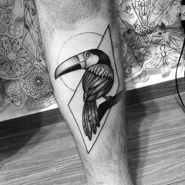 Geometric toucan tattoo on calf with fine dotwork shading, sharp lines, and abstract shapes for a modern black-and-grey style.