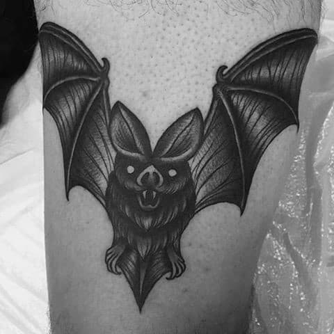 Black and grey traditional bat tattoo with spread wings, detailed shading, and glowing white eyes for a bold look.