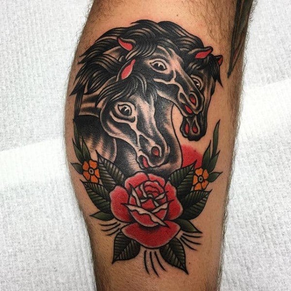 Traditional horse tattoo featuring three black horse heads with red highlights, framed by a red rose and green leaves.