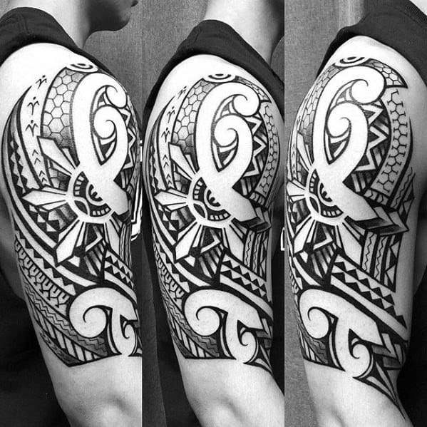 Filipino sun tattoo on the upper arm with bold tribal detailing, intricate patterns, and strong black-and-white contrast in a half-sleeve style.
