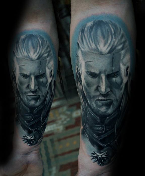 Bold forearm tattoo of Geralt’s face from The Witcher, with glowing eyes, framed in blue hues and detailed with the wolf medallion.