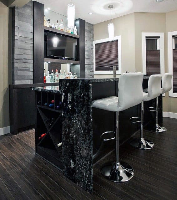 Modern bar with high stools, a black marble counter, and shelves displaying bottles under soft lighting
