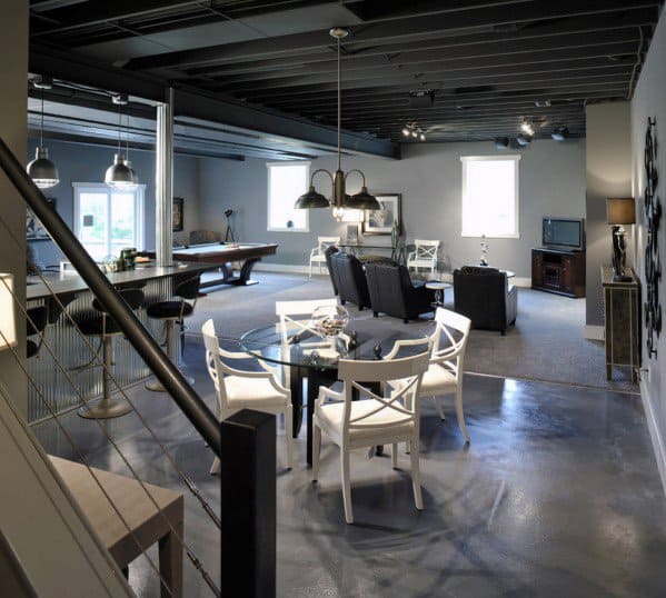 Modern basement man cave with seating area, pool table, TV, and dining table under industrial lighting