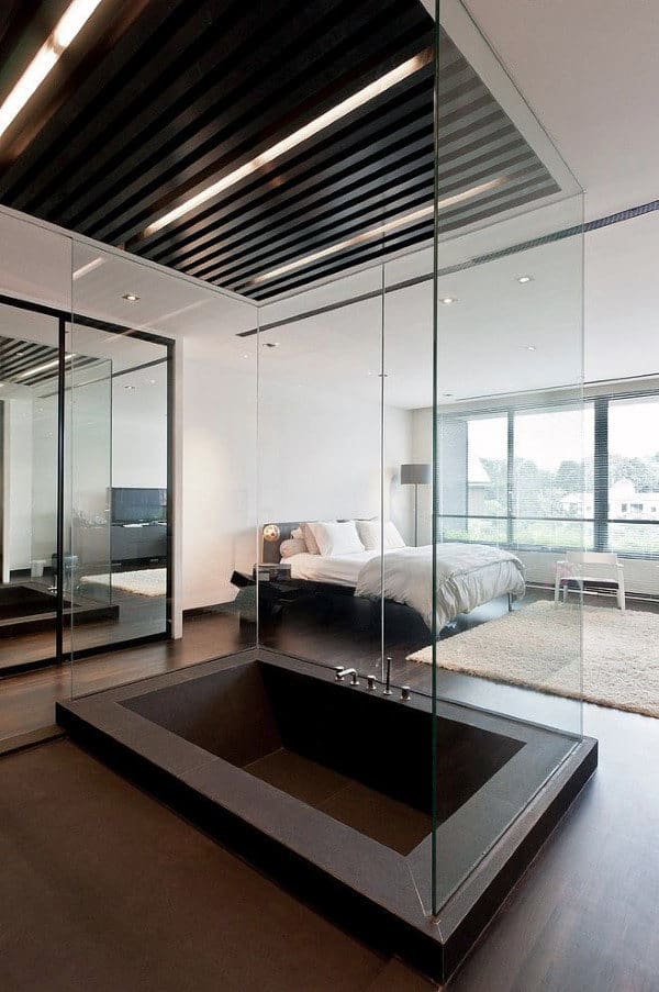 Modern bedroom with a sunken bathtub, large windows, and glass partitions