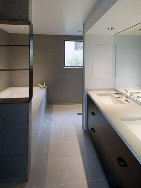 Modern bathroom with dual sinks, large mirror, and a tub next to a window