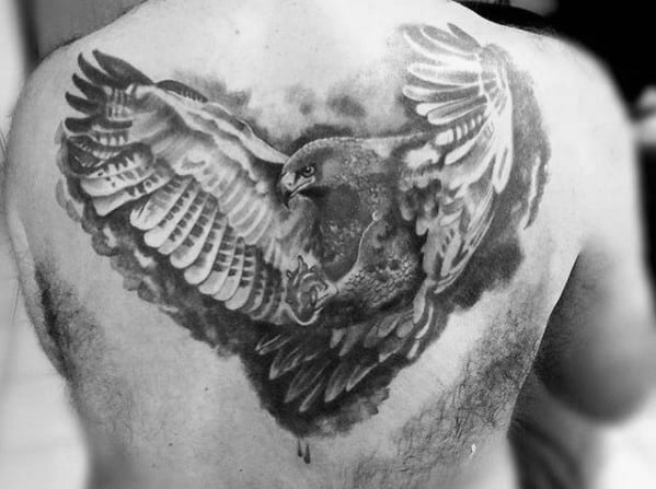 Back tattoo of a detailed, realistic eagle with wings spread wide in black and grey ink