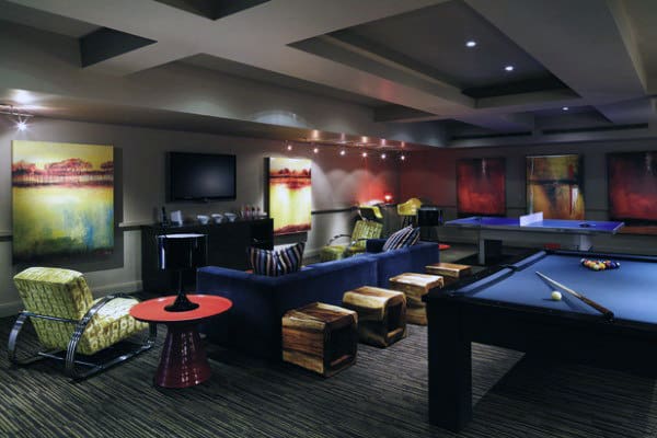 A modern game room with a pool table, abstract art, and cozy seating under soft lighting