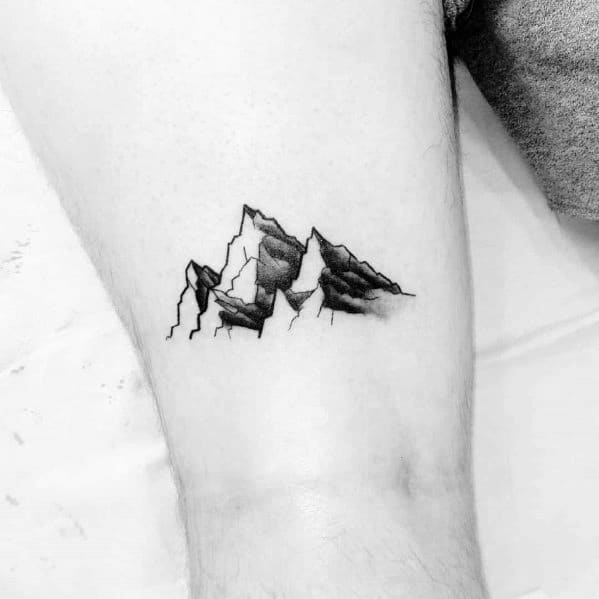 Minimalist mountain tattoo on the arm, featuring sharp peaks with fine line details and subtle shading for a bold yet simple design.