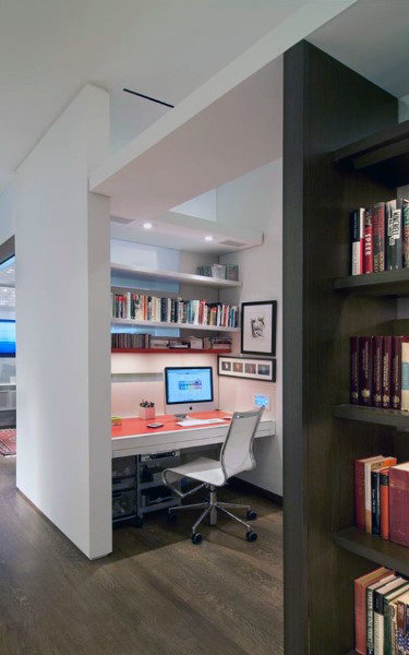 Modern home office with a desk, computer, chair, and bookshelves filled with books