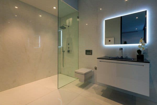 Modern bathroom featuring a glass shower, wall-mounted toilet, sleek sink, and a chic backlit mirror