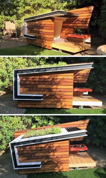 Modern wooden dog house with an angular design, green roof, and shaded dog rest area in a garden setting