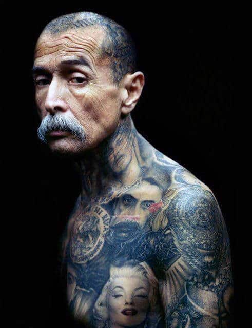 Elderly man with extensive tattoos covering his upper body and face