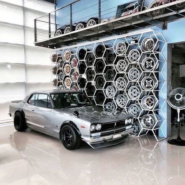 A stylish garage featuring a classic Nissan Skyline and a unique hexagonal wheel storage display.